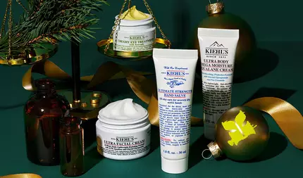 Koyu yeşil dokulu bir arka plan uzerine yerleştirilen şık bir grafik, Kiehl’s urunlerini ve tatil suslerini one cıkarıyor. Soluk sarı kremi gorunen acık beyaz "KIEHL’S CREAMY EYE TREATMENT WITH AVOCADO" kavanozu, altın bir terazinin uzerinde bir cam dalıyla dengelenmiş. Beyaz kremi gorunen beyaz "KIEHL’S ULTRA FACIAL CREAM" kavanozu, beyaz tupte "KIEHL’S ULTIMATE STRENGTH HAND SALVE" ve beyaz tupte "KIEHL’S ULTRA BODY MEGA MOISTURE SQUALANE CREAM" yuzey uzerinde duzenlenmiş. İki kehribar cam şişe, altın bir kurdele ve uzerinde sarı bir “K” logosu bulunan altın bir yuvarlak sus de bu şenlikli tasarımın bir parcası.