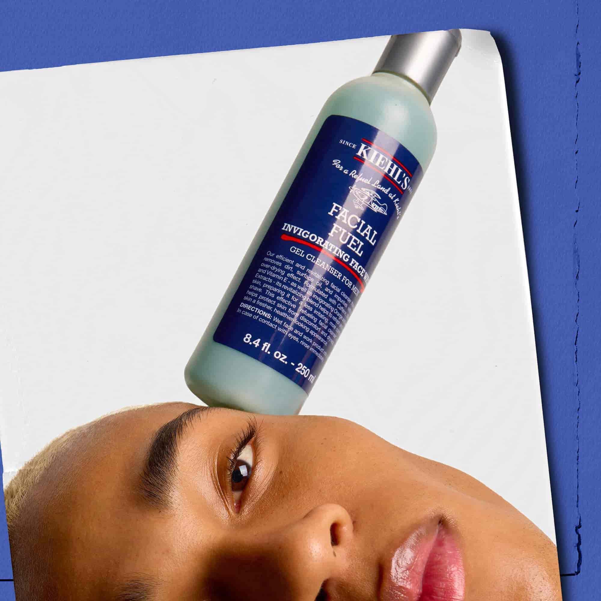 Model, yuzunde dengelenmiş Kiehl's Facial Fuel Energizing Face Wash şişesi ile.