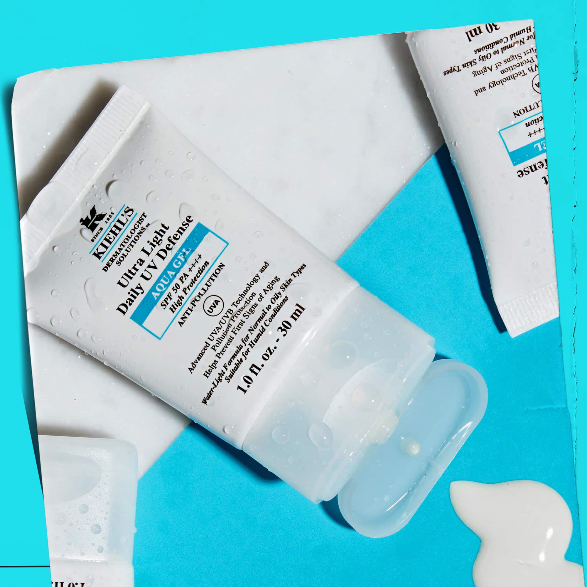 A flat-lay of multiple Ultra Light Daily UV Defense Aqua Gel tubes on a marble surface, showcasing their lifestyle appeal.