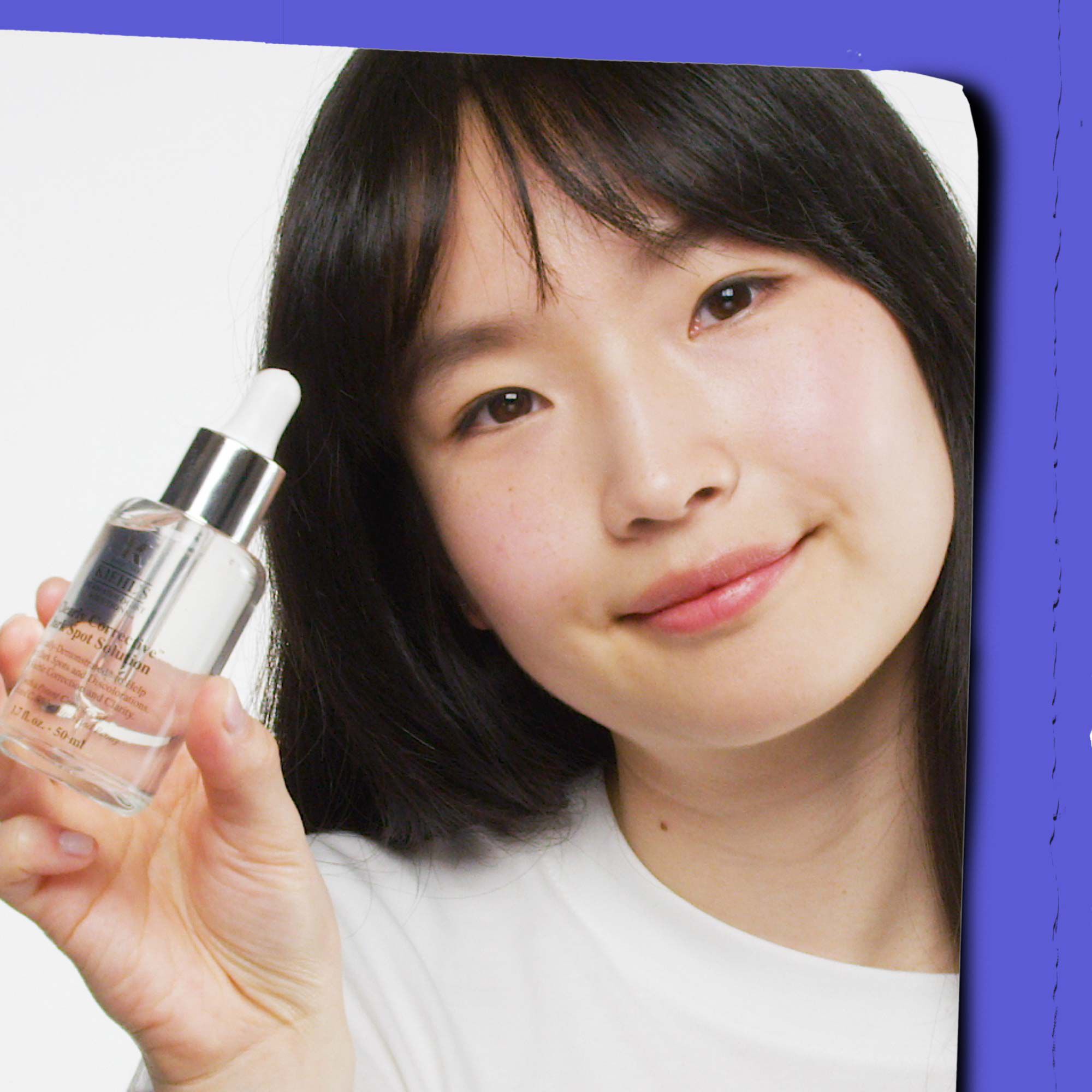 A person with dark hair holds p a clear dropper bottle containing a transparent liquid against a white background with a blue border.