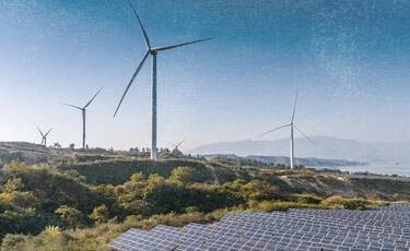 Landscape featuring wind turbines and solar panels under a clear blue sky, representing the brand’s commitment to using renewable energy for manufacturing.