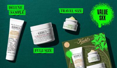 Bir Kiehl’s hediye seti, yeşil, altın ve neon yeşili suslemelerle dekore edilmiş bir kutunun onunde, uc urunle birlikte gosterilmektedir. Urunler arasında Calendula Deep Cleansing Foaming Face Wash, Creamy Eye Treatment with Avocado ve Ultra Facial Cream yer almaktadır. Ambalajlarda Kiehl’s logosu ve şenlikli tatil tasarımları bulunmaktadır.